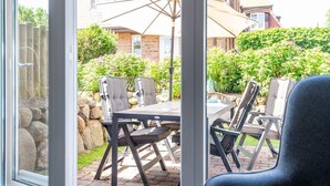 Eine Terrasse mit Tisch und Stühlen, eine Steinmauer und ein Haus im Hintergrund.