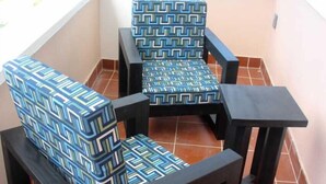 Un balcón con dos sillas y una mesita, con tapicería de estampado geométrico.