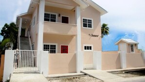 Un edificio de dos pisos con fachada color beige, una puerta roja y una placa que dice "James".
