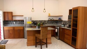 Una cocina moderna con una isla central, armarios de madera, horno integrado e iluminación colgante.