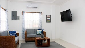 Una sala de estar con dos sofás, una mesa de centro y un televisor de pantalla plana montado en la pared.