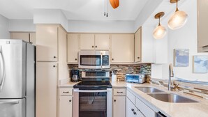 Une cuisine moderne dotée d’appareils électroménagers en acier inoxydable, de meubles de couleur beige et d’un tapis à motifs.