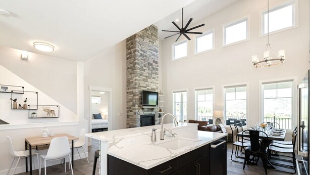 A spacious kitchen with a large island, a stone accent wall, and a dining area with a view. - Luxury Mountain Retreat - Hot Tub + Views!  (Granby)