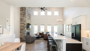 A spacious kitchen with a stone accent wall, a large island, and a modern chandelier. - Luxury Mountain Retreat - Hot Tub + Views!  (Granby)
