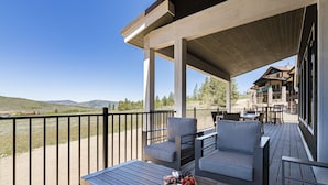A covered outdoor seating area with a table set with food, overlooking a scenic landscape. - Luxury Mountain Retreat - Hot Tub + Views!  (Granby)