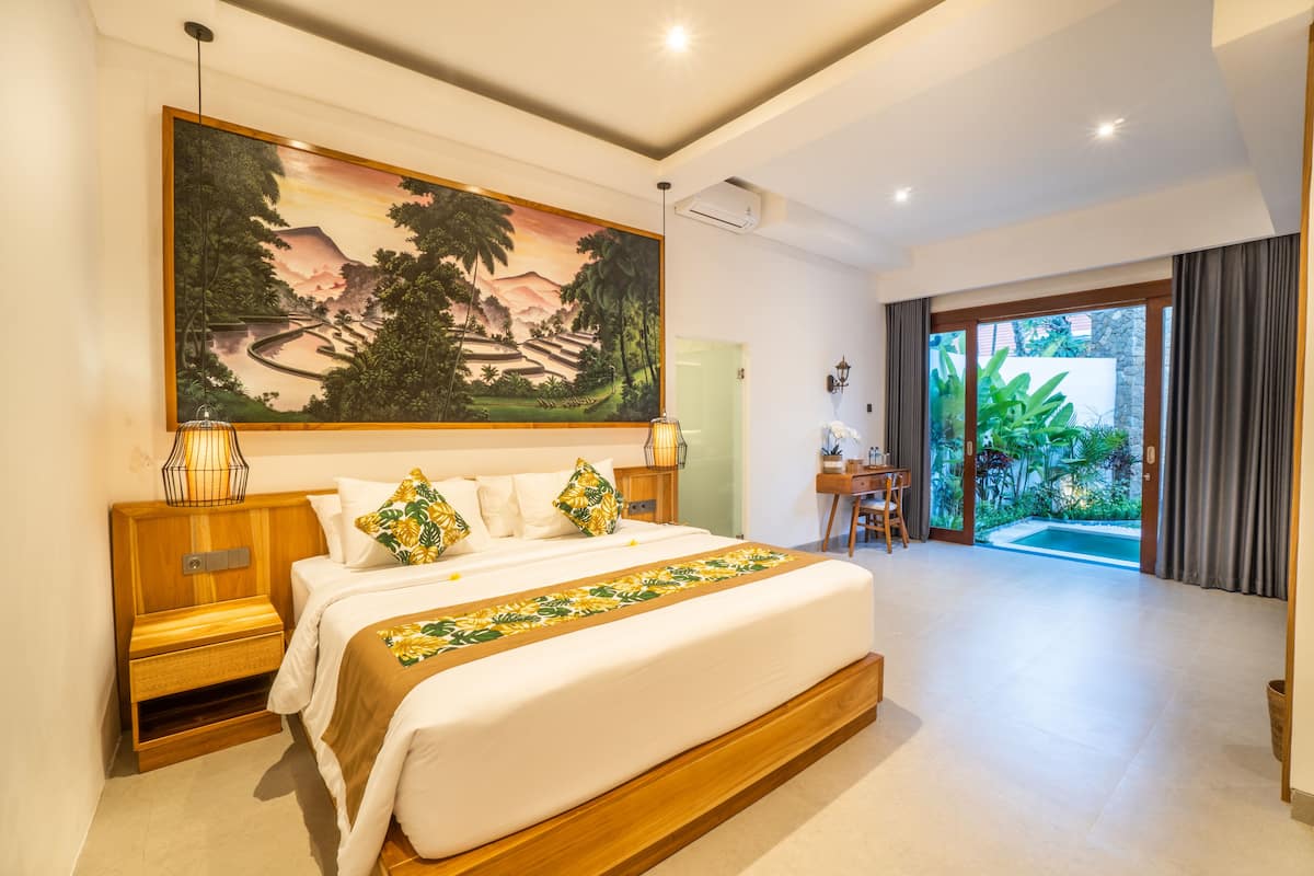 A spacious bedroom with a large bed, a painting above the bed, and a view of a pool through the glass door.