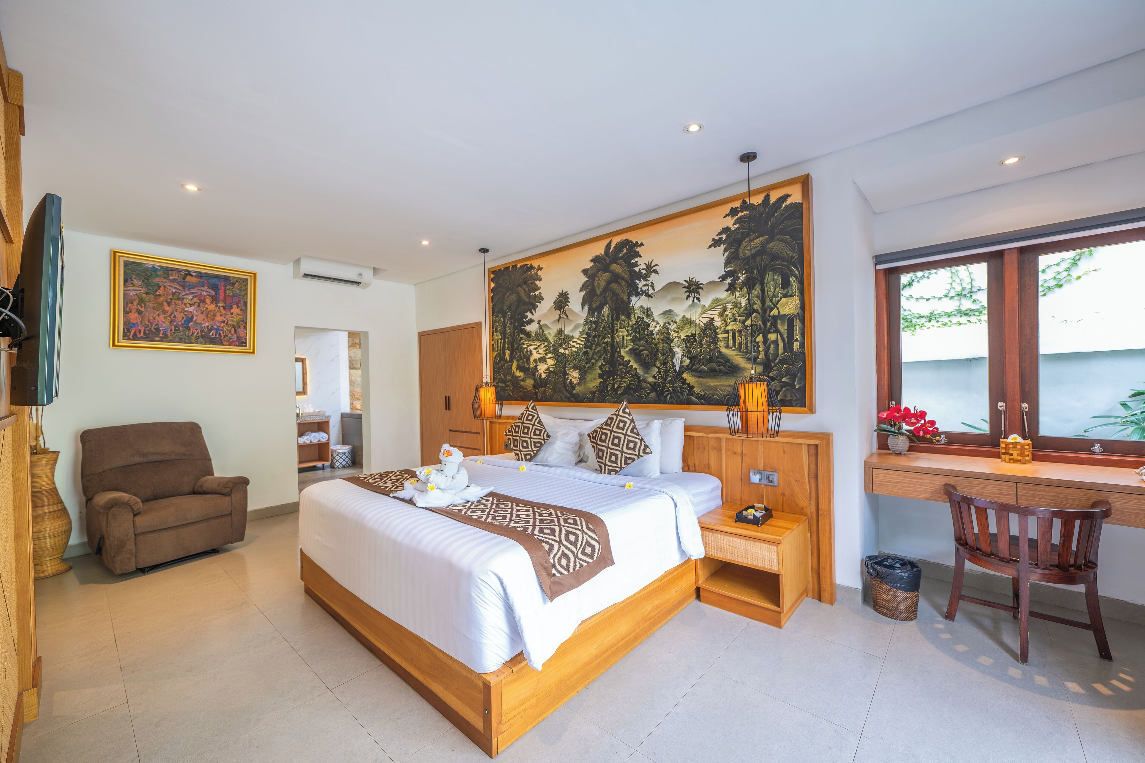 A spacious bedroom with a large bed, a wooden desk, a chair, and a painting on the wall.