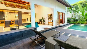 A modern house with a pool, outdoor seating, and a well-lit interior. - Alam Jepun Villa  (Legian)