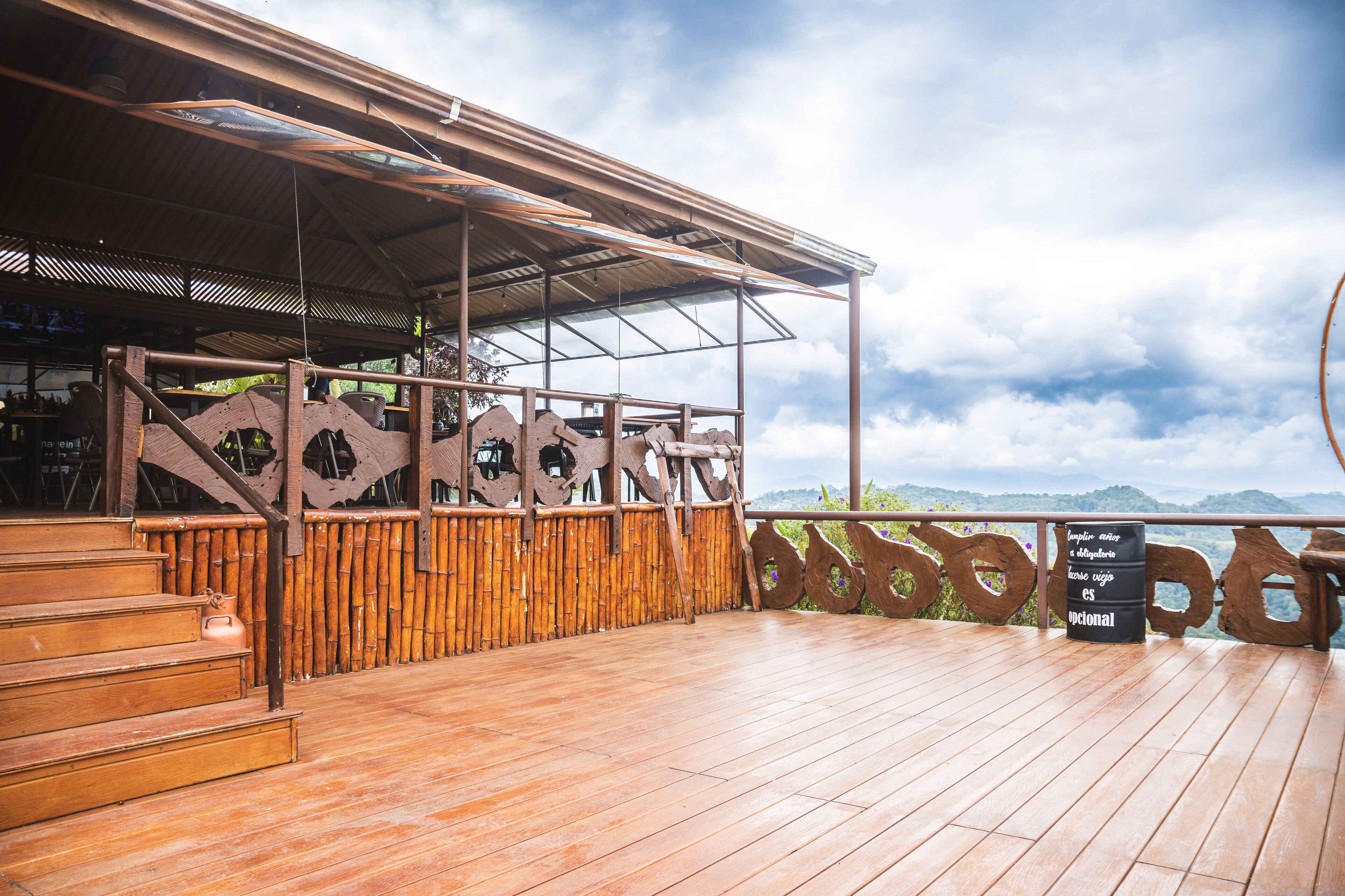 A wooden deck with a metal railing, bamboo fence, and a sign.