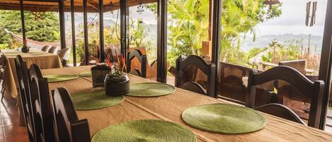 A restaurant with a long wooden table, green placemats, and chairs.