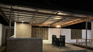 Ulkoterassi, jossa on kivinen baaritiski, oleskelualue ja pergola.