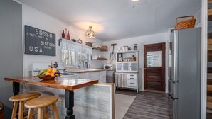 A kitchen with a wooden island, stools, a refrigerator, and a sign on the wall. - The Bigfork Riverside Retreat - No Cleaning Fee! (Bigfork)