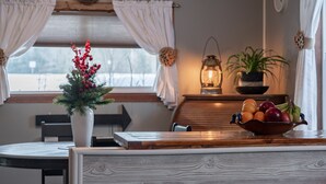 A dining area with a wooden table, a white vase with red berries, a bowl of fruit, a lantern, and a potted plant. - The Bigfork Riverside Retreat - No Cleaning Fee! (Bigfork)