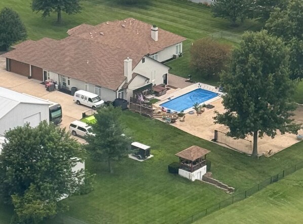 Vista aérea de una propiedad residencial con piscina, garaje independiente y un cobertizo pequeño.