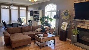 Amplia sala de estar con sofá modular, una mesa de centro, chimenea y televisor.