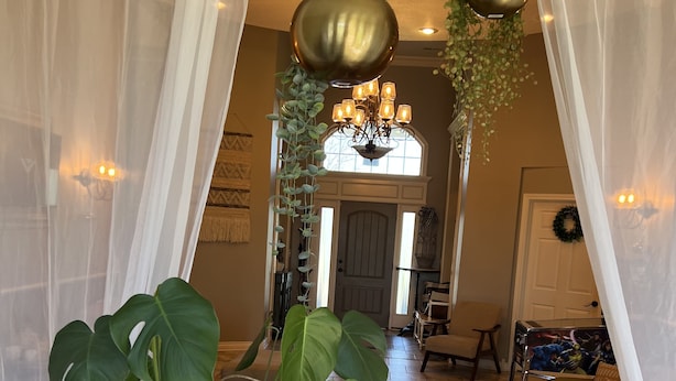 A living room with a large potted plant, a brown leather sofa, and a chandelier. - Estate Home Hot Tub Beach view Wi-Fi 8 acres 5000 sqft 4 bd 3.5 bath (Greenwood)