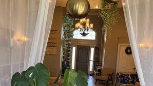 Una sala de estar con una planta grande en maceta, un sofá de cuero marrón y una araña.