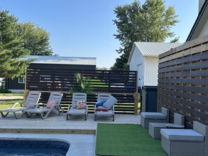 A poolside area with lounge chairs, a small pool, and a wooden deck.