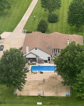 A two-story house with a swimming pool, a covered patio, and a fenced yard.