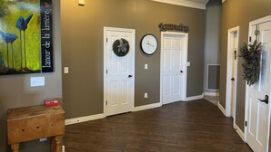 A hallway with two white doors, a wall clock, and a painting. - Estate Home Hot Tub Beach view Wi-Fi 8 acres 5000 sqft 4 bd 3.5 bath (Greenwood)