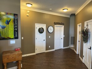 A hallway with two white doors, a wall clock, and a painting.