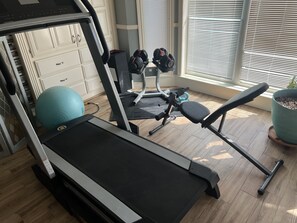A home gym with a treadmill, exercise balls, and weights.