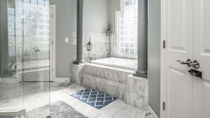 A bathroom with a marble bathtub, a glass shower enclosure, and a large window. - Estate Home Hot Tub Beach view Wi-Fi 8 acres 5000 sqft 4 bd 3.5 bath (Greenwood)