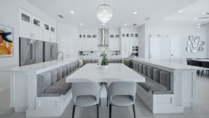 A modern kitchen with a central island, built-in appliances, and a chandelier. - 9BR Reunion Mansion | Pool, Spa & Home Theater (Kissimmee)