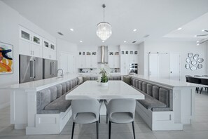 Une cuisine moderne dotée d’un îlot central, d’appareils électroménagers intégrés et d’un lustre.