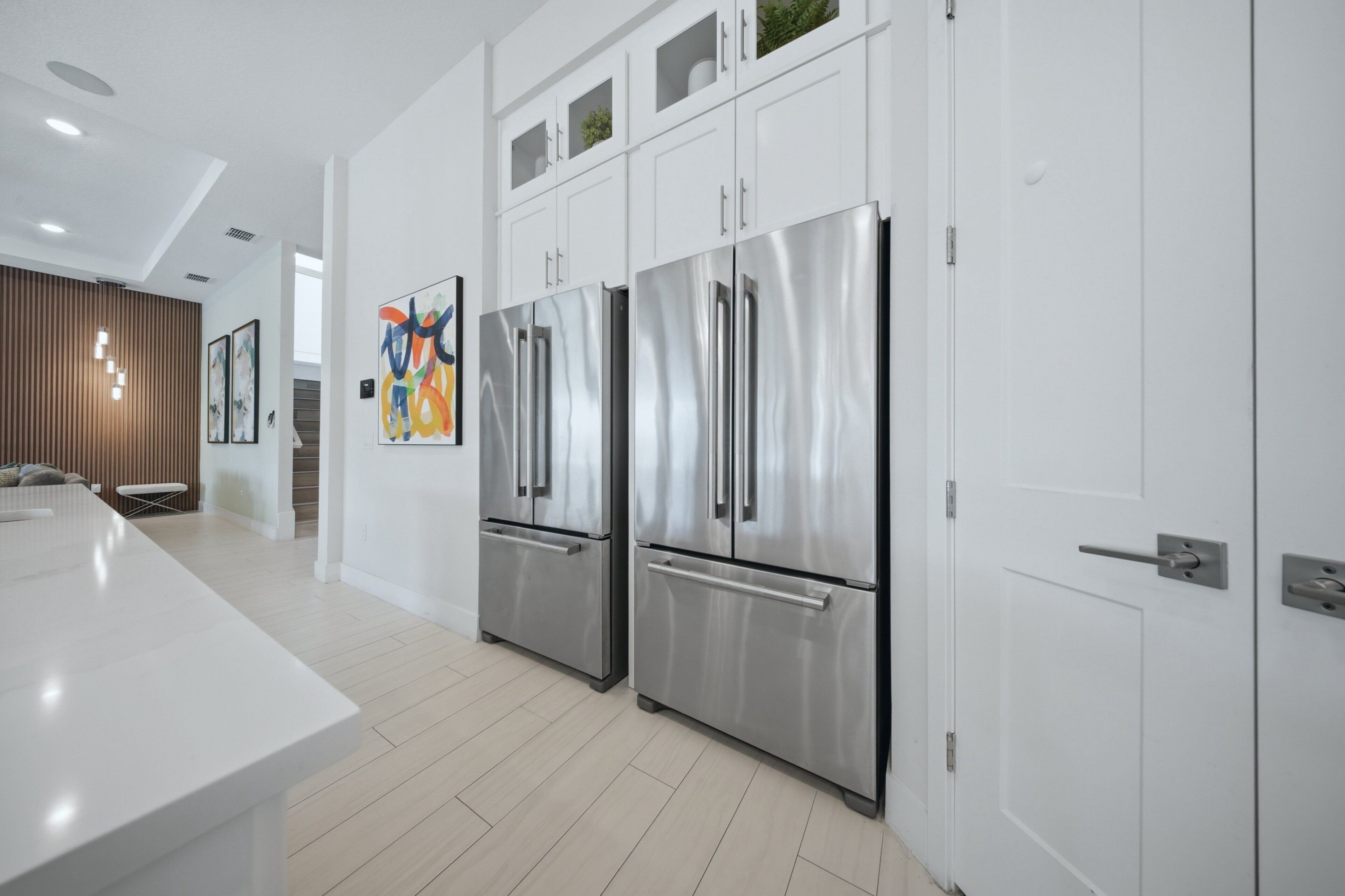 Een moderne keuken met roestvrijstalen apparatuur, witte kasten en een groot eiland.
