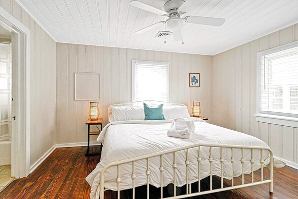 A bedroom with a white bed, wooden flooring, a ceiling fan, and two bedside lamps. - Beachwalk #2, 8 minute walk to the Beach! (Virginia Beach)