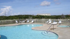 A swimming pool with lounge chairs and a view of a building in the background. - Cape Hatteras Motel (Buxton)