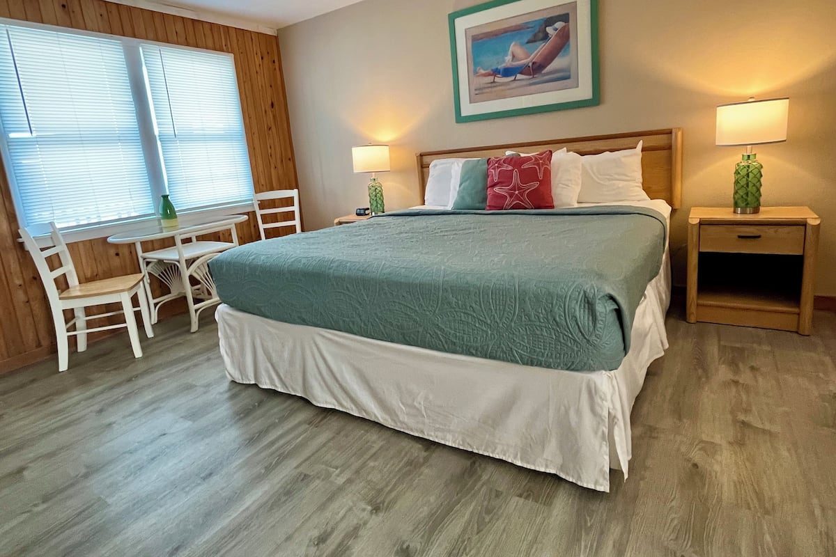 Une chambre bien rangée, avec un lit, des tables de chevet, une chaise et une petite table.