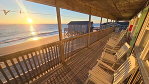 A wooden deck with rocking chairs overlooking a beach at sunset. - Cape Hatteras Motel (Buxton)