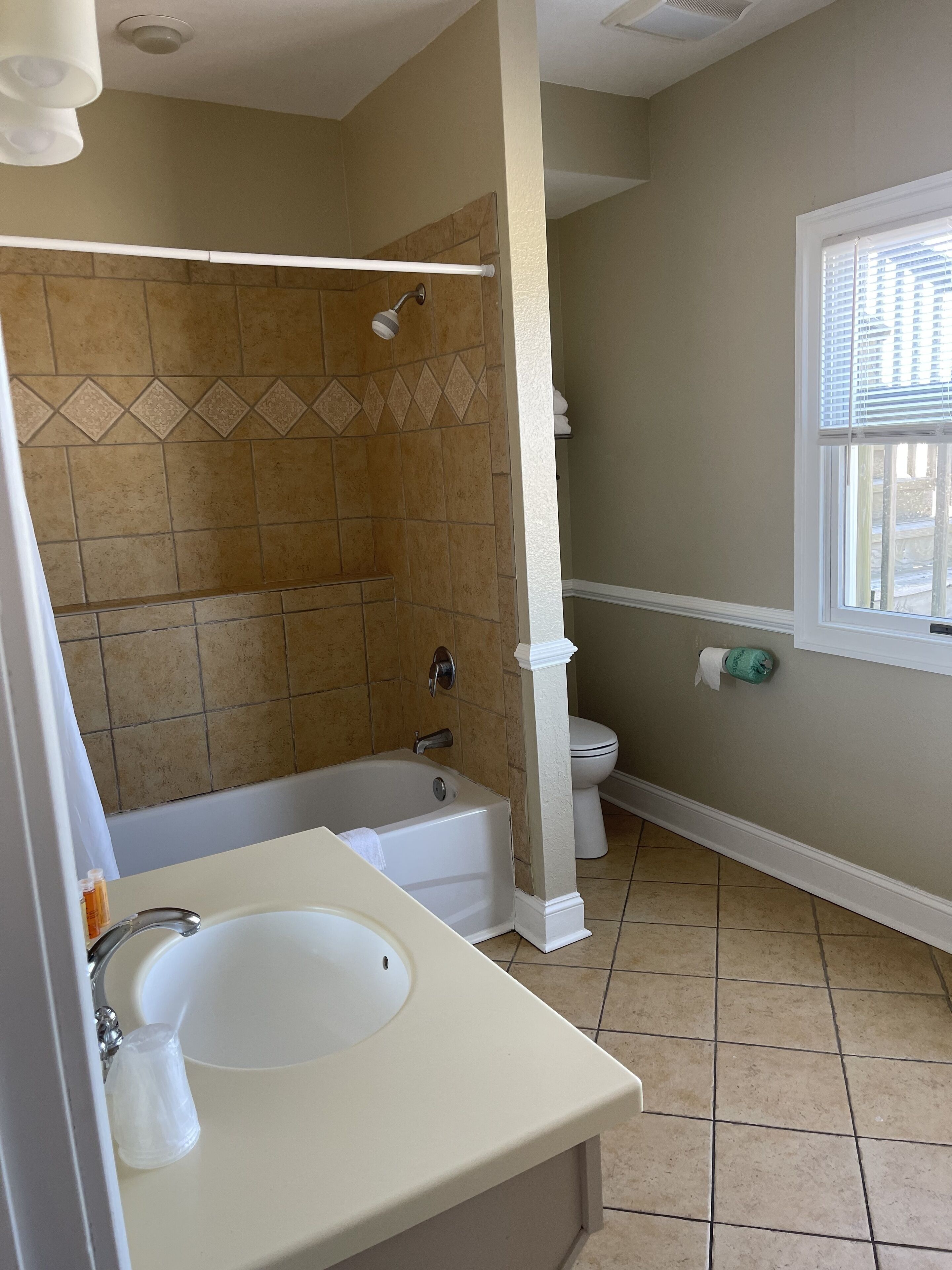 Un baño con bañera, lavabo, inodoro y ventana.