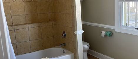 Un baño con bañera, lavabo, inodoro y ventana.