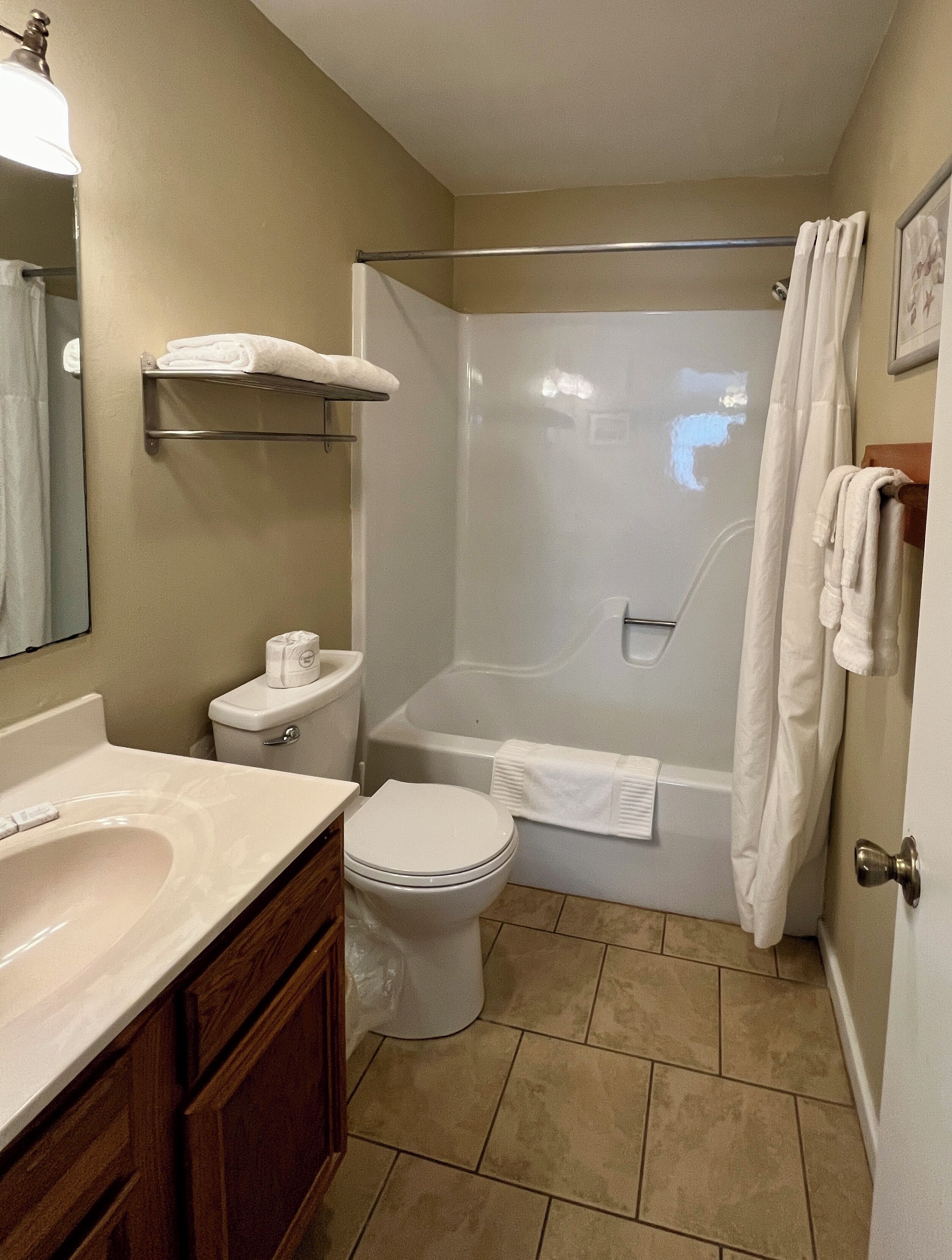 Une salle de bain équipée de toilettes, d’un lavabo, d’une baignoire et d’un rideau de douche.