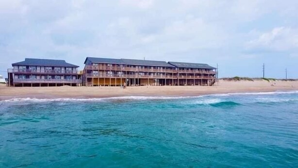 A beachfront hotel with multiple floors and balconies, located directly adjacent to the sandy beach. - Cape Hatteras Motel (Buxton)