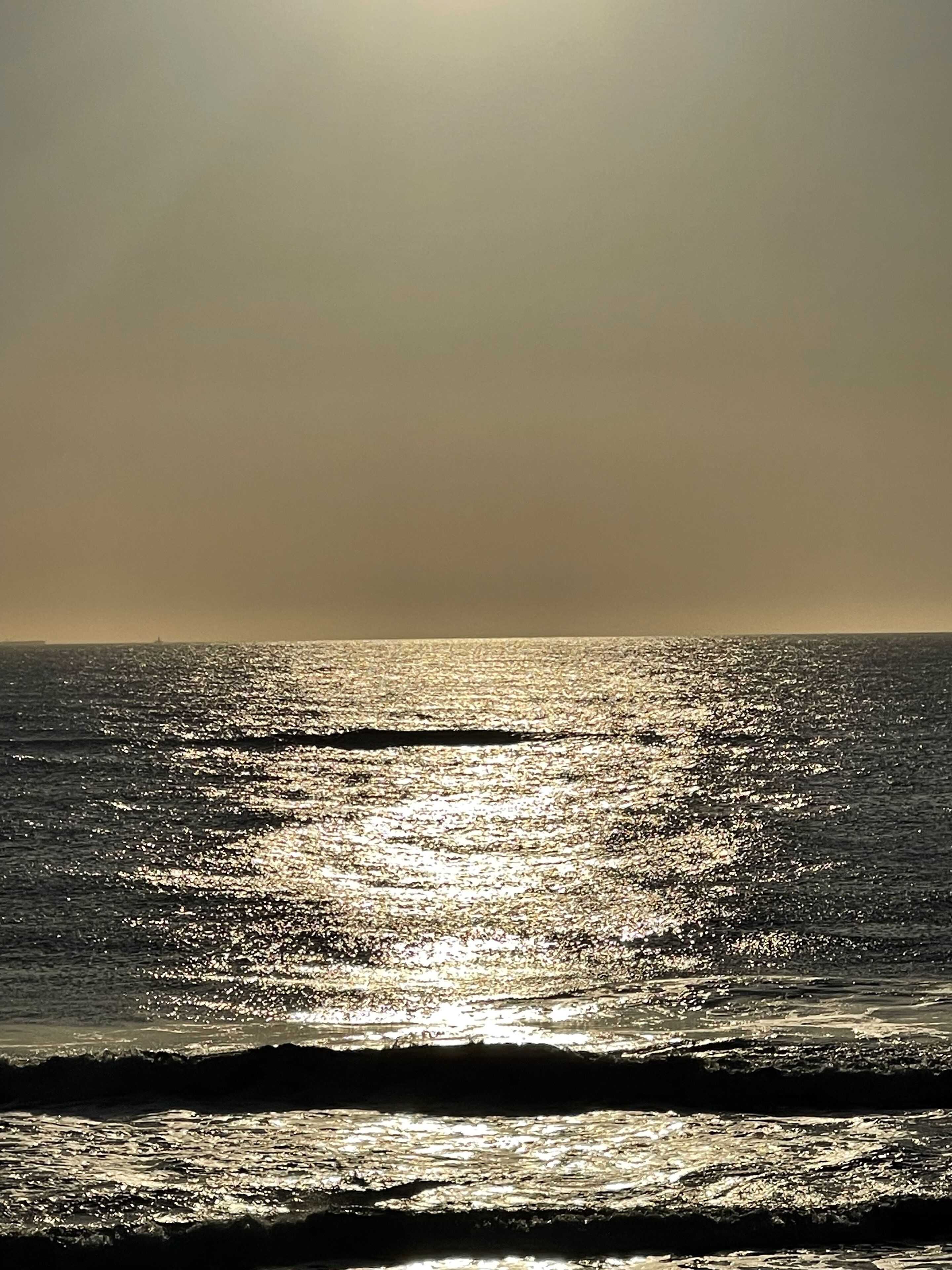 A beach with sunlight reflecting off the water.