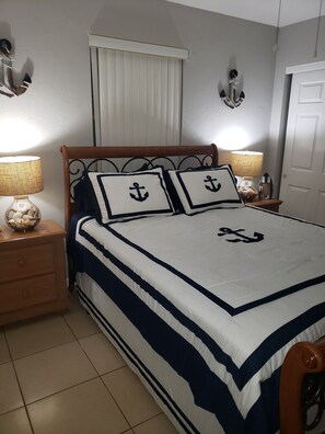A bedroom with a bed, two nightstands, a window with blinds, and wall-mounted lamps. - Your Perfect Getaway 4 bedroom residential home (Port St Lucie)
