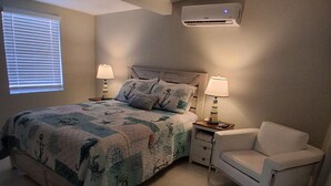Een slaapkamer met een bed, twee nachtkastjes met lampen, een stoel en een raam met jaloezieën.