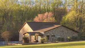 Une maison en pierre avec un toit en pente, un porche à l’avant et une pelouse bien entretenue.