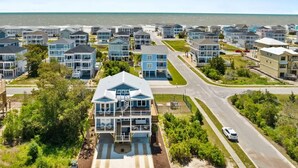 Un quartier résidentiel situé sur la côte, avec des maisons modernes, une route et une vue sur l’océan.