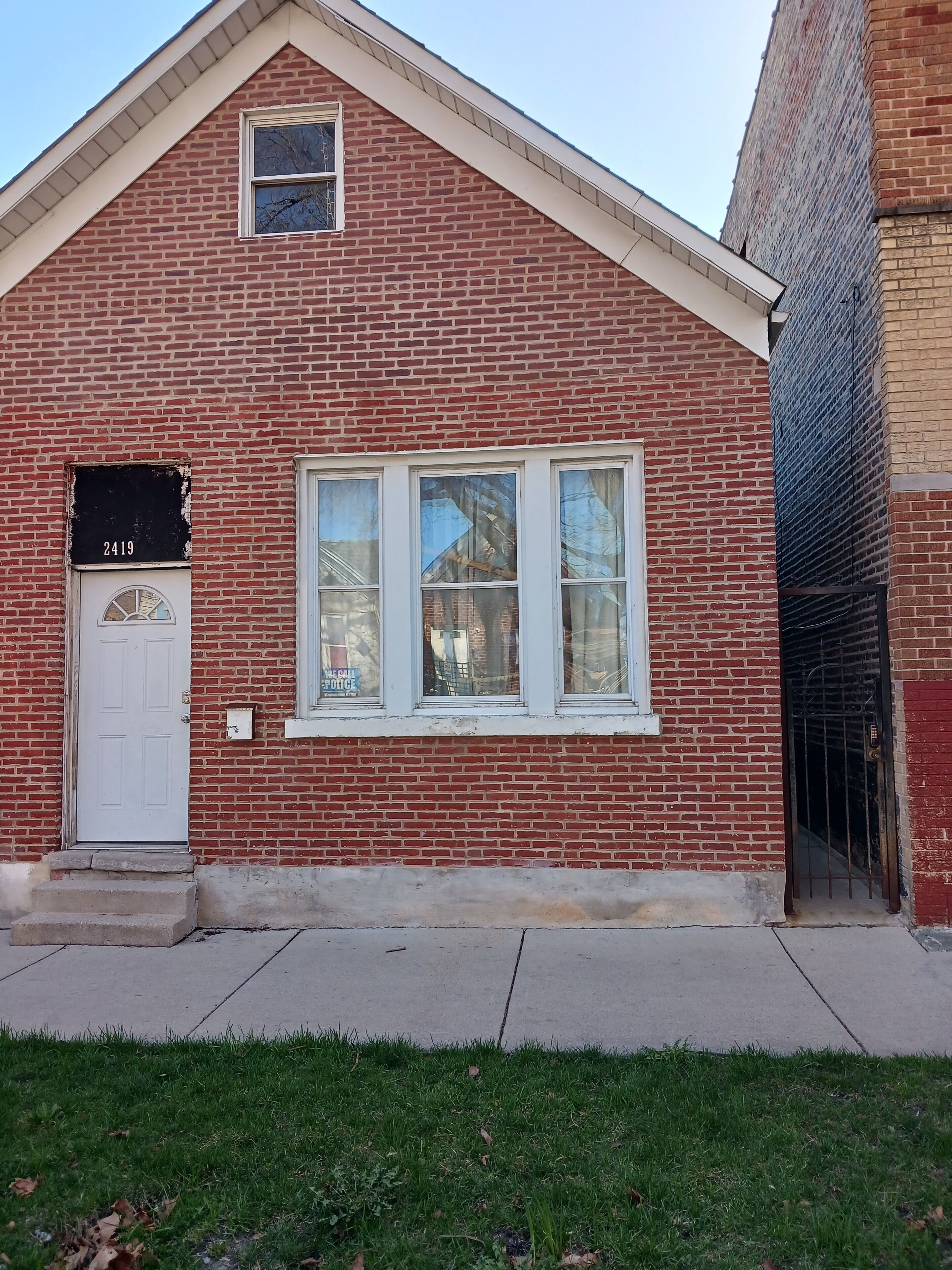 A red brick building with a white door, numbered 2419, and a garage door.