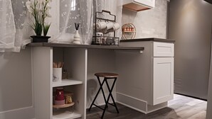 A compact kitchen with a built-in island, white cabinetry, and a small stool.