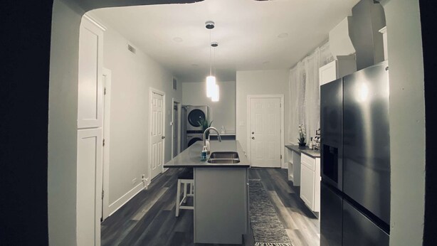 A modern kitchen with white cabinetry, a stainless steel refrigerator, and a central island with a sink.