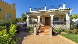 Una casa de dos pisos con un patio empinado, una puerta de madera y un balcón con barandilla.
