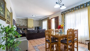 Un comedor con una mesa y sillas de madera, un sofá y una planta en maceta.