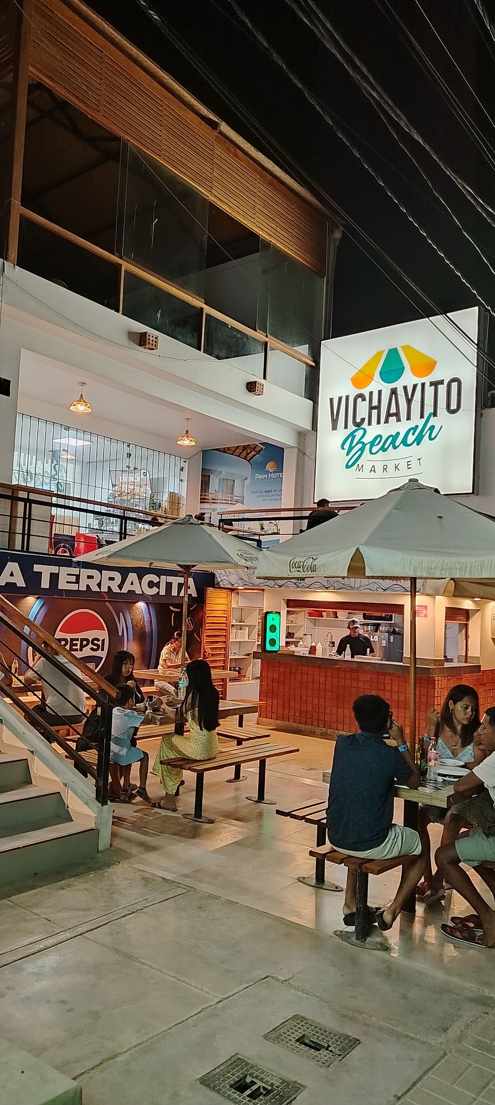 An indoor market with a vending machine labeled "VICHAYITO Beach Market" and a Coca-Cola branded kiosk.