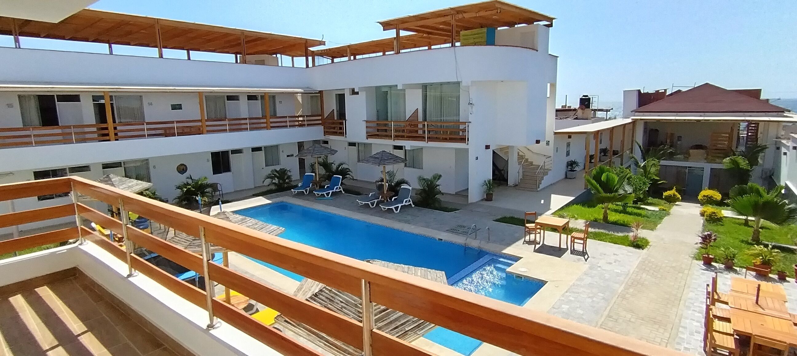 A multi-level building with a central swimming pool, outdoor seating, and a garden area.